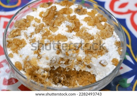 Konafa topped with whipped cream, raisins, walnuts, shredded coconut and stuffed with cream and fresh mango layer and soaked with honey sugar syrup, Eastern Turkish and Egyptian kunafa with manga
