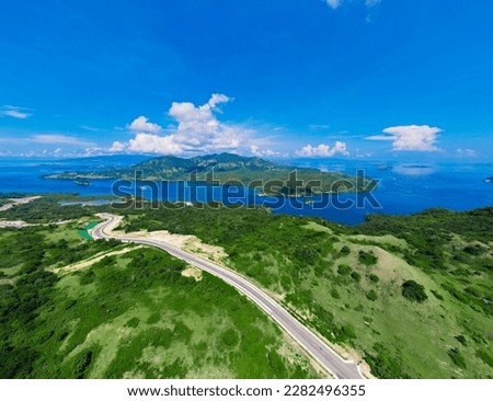Aerial view of green meadows, hills and the road. Top view from drone of rural road mountains. Beautiful landscape with roadway, green grass, sky with clouds in Golo Mori, Labuan Bajo Flores Indonesia Royalty-Free Stock Photo #2282496355