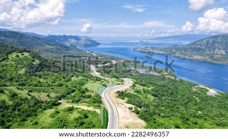 Aerial view of green meadows, hills and the road. Top view from drone of rural road mountains. Beautiful landscape with roadway, green grass, sky with clouds in Golo Mori, Labuan Bajo Flores Indonesia Royalty-Free Stock Photo #2282496357