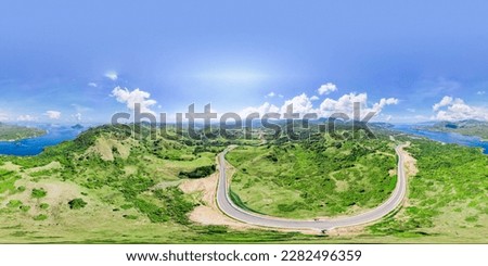 Aerial view of green meadows, hills and the road. Top view from drone of rural road mountains. Beautiful landscape with roadway, green grass, sky with clouds in Golo Mori, Labuan Bajo Flores Indonesia Royalty-Free Stock Photo #2282496359