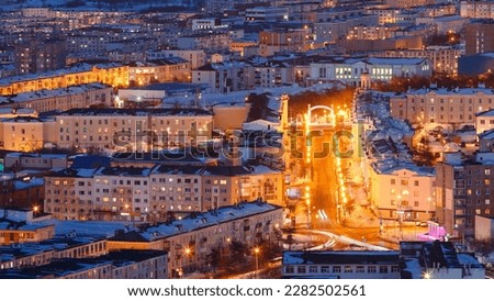 Beautiful evening cityscape with bright street lighting at dusk. Aerial landscape with many buildings. Portovaya street and the arch with the text in Russian "City Park". Magadan city, Far East Russia Royalty-Free Stock Photo #2282502561