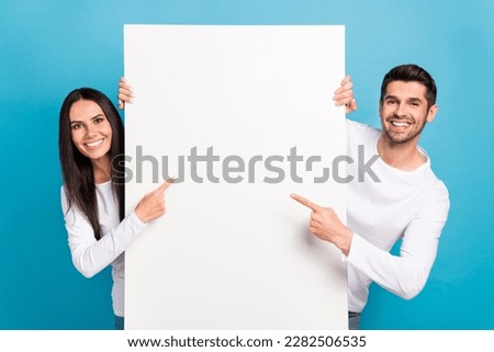 Photo of two positive nice people indicate finger empty space proposition isolated on blue color background