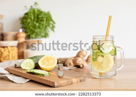 Infused  water with cucumber, lemon and ginger in glass bottle on wooden table. Diet, detox, healthy eating, weight loss concept Royalty-Free Stock Photo #2282513373
