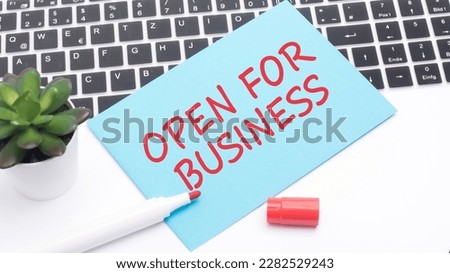 text OPEN FOR BUSINESS on blue card on laptop keyboard. white background. business and finance concept.