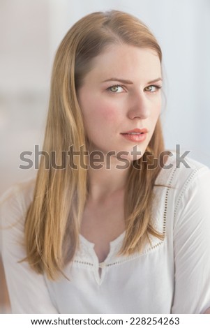 Portrait of a blonde woman posing looking at camera at home in the living room