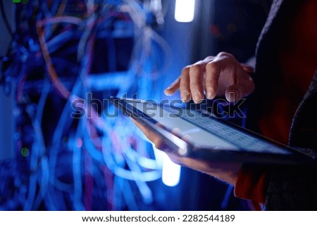 Closeup hand working in digital tablet in server room Royalty-Free Stock Photo #2282544189