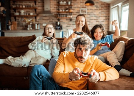 Young family playing video games together in the living room on a gaming console Royalty-Free Stock Photo #2282546877