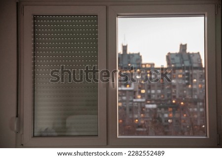 Selective blur on PVC windows, in plastic, one covered with roller shutters, in an urban environment of Serbia with residential high rise buildings in background. Royalty-Free Stock Photo #2282552489