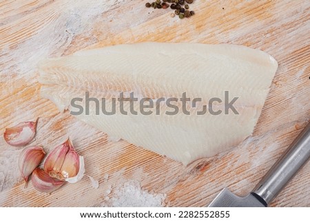 Uncooked fillet halibut fish with parsley and garlic on wooden table