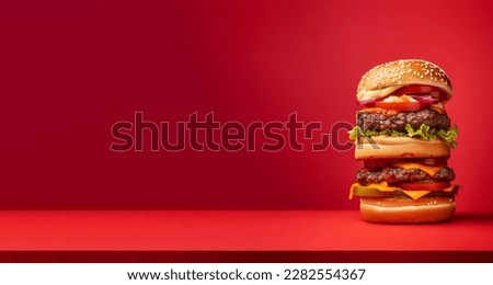 A very tall hamburger, over a red background Royalty-Free Stock Photo #2282554367