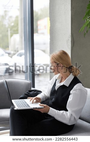 Pensive woman copywriter using laptop computer, typing on keyboard, working freelance project at workplace. Portrait of middle aged successful manager checking email sitting in modern office