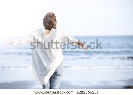 Woman taking deep breaths and stretching on sandy beach Stress free Royalty-Free Stock Photo #2282566251