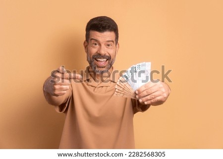 fun mature man with brazil banknotes currency in beige colors. business, loan, pay, wealth concept.