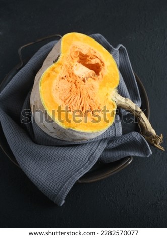 Close up and top view of fresh yellow pumpkin squash, cut into half over dark background 