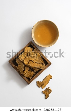 Top view of medicine cup, some rhizoma rhei on square wooden tray on white background. Photo for medicine advertising, photography traditional medicine content.