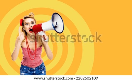 Happy excited woman hold mega phone loudspeaker and shout something. Blond girl in pin up style with wide open mouth, over orange yellow spiral background. Female model in retro vintage ad concept Royalty-Free Stock Photo #2282602109
