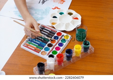Closeup student is studying art subject, painting, art activity, enjoy and concentrate on favorite activity with many colors. Concept, Education. Learning by doing, enhance kid's imagination.         