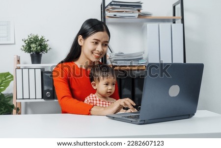 Young business mom asian people woman with baby girl watching video social on laptop computer in the room.