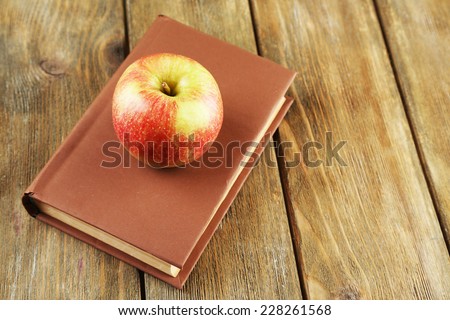 Apple with book on wooden background