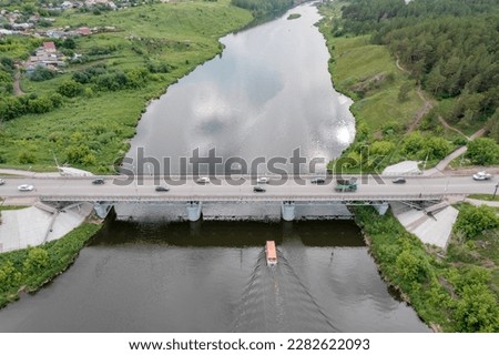 bridge across the river where cars drive. a ship is sailing on the river