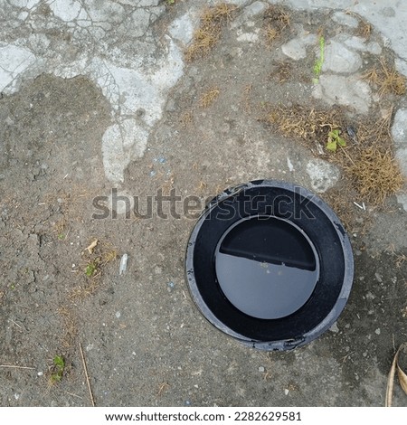 Black bucket containing water with background of cement