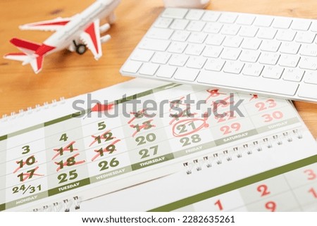 Calendar and reminders for business trip, travel and vacation. planner with airplane model on desktop with keyboard, mouse, coffee and succulent. marking important dates and days in a diary at the off