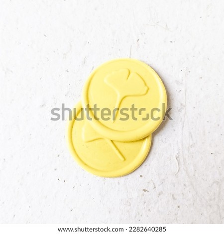 Two pieces of pastel yellow ginko leaf pattern wax stamp or wax seal coin on a white background. Can be use for vintage antique wedding invitation or decoration