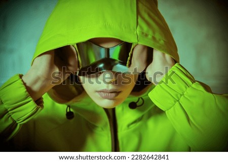 Portrait of a modern hip-hop dancer. Stylish girl in green hoodie and sunglasses poses at studio on a grunge background. Youth style.