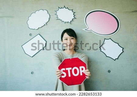 A young woman with a empty balloon. Has a stop traffic sign.