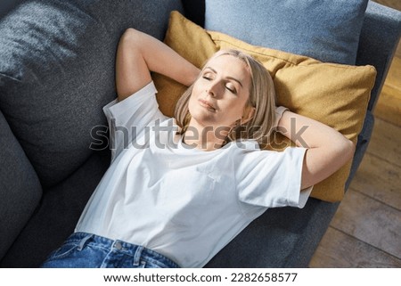 Overhead picture of adult woman taking a nap during the day sleeping on a sofa at home