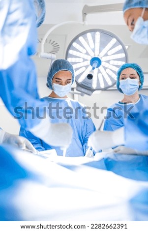 Group of surgeons wearing safety masks performing operation. Medicine concept. surgery, medicine and people concept - group of surgeons at operation in operating room at hospital Royalty-Free Stock Photo #2282662391