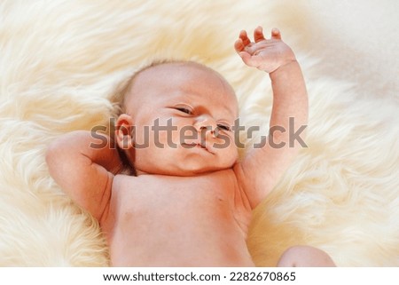 Baby girl, 3 months, lying on a sheepskin