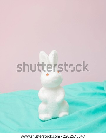 White Easter bunny on mint green material and pink background.