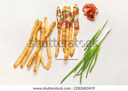 Board of tasty Italian Grissini with bacon on light background Royalty-Free Stock Photo #2282683419