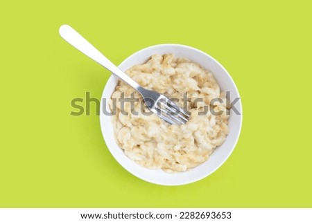 Mashed bananas in bowl on green background.