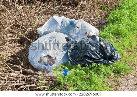 Illegal dumping with plastic bags abandoned in nature Royalty-Free Stock Photo #2282696009