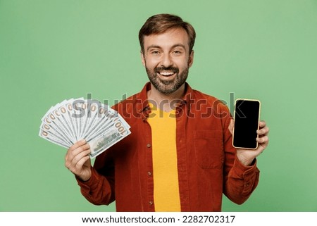 Elderly man 40s years old wears casual clothes red shirt t-shirt old in hand fan of cash money in dollar banknotes use blank screen mobile cell phone isolated on plain pastel light green background