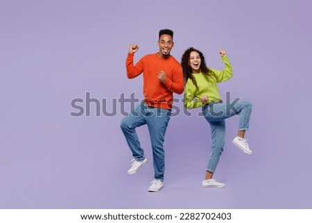 Full body young couple two friends family man woman of African American ethnicity wear casual clothes together doing winner gesture celebrate clenching fists isolated on plain light purple background
