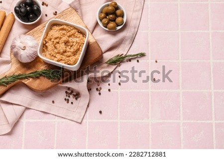 Bowl with tasty hummus on pink tile background