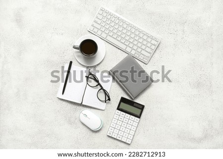Composition with eyeglasses, blank notepad and coffee on light grunge background