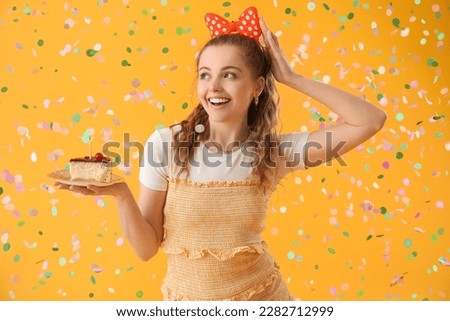 Happy young woman with piece of Birthday cake on yellow background