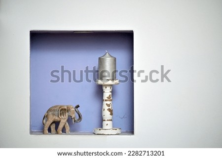 Interior design with static nature elefant heading to a candle on wooden candle holder inside a niche on the wall, inspirational decoration quote
