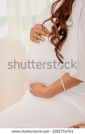 This is a picture of a pregnant woman holding her tummy with love and excited for the coming of their baby.