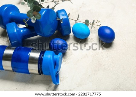 Sports water bottle, dumbbells, Easter eggs and eucalyptus branches on grunge background, closeup