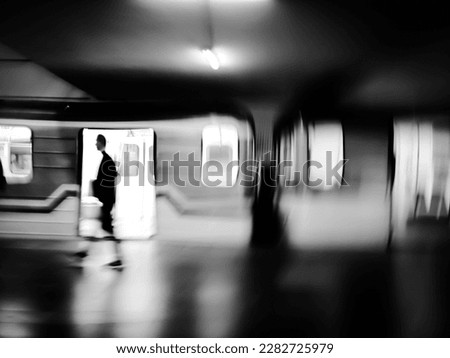Black and white motion blur image of subway with a train and passengers.