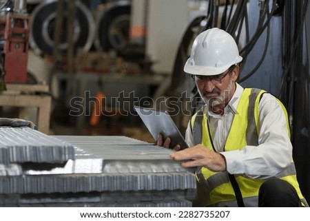 Senior male factory worker inspecting quality galvanized or metal sheet in factory. Mature male worker working checking metalwork sheet in warehouse during manufacturing process in plant Royalty-Free Stock Photo #2282735207