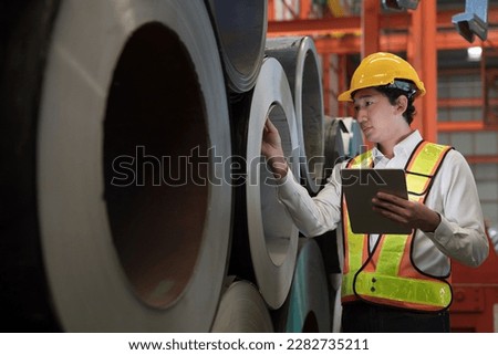 Asian male factory worker inspecting quality rolls of galvanized or metal sheet in factory. Asian male worker working in warehouse of raw materials. Metalwork during manufacturing process in plant Royalty-Free Stock Photo #2282735211
