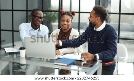 African american business team talking about strategy while looking at laptop, in office Royalty-Free Stock Photo #2282746253