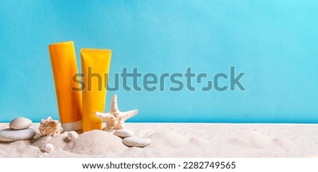 Sunblock lotion bottles, starfish, sea shells and sunglasses on blue background with beach sand, copy space, banner. Summer beach, vacation concept, spf uv-protect cosmetics. Royalty-Free Stock Photo #2282749565