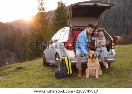 Parents, their daughter and dog near car in mountains, space for text. Family traveling with pet Royalty-Free Stock Photo #2282749819